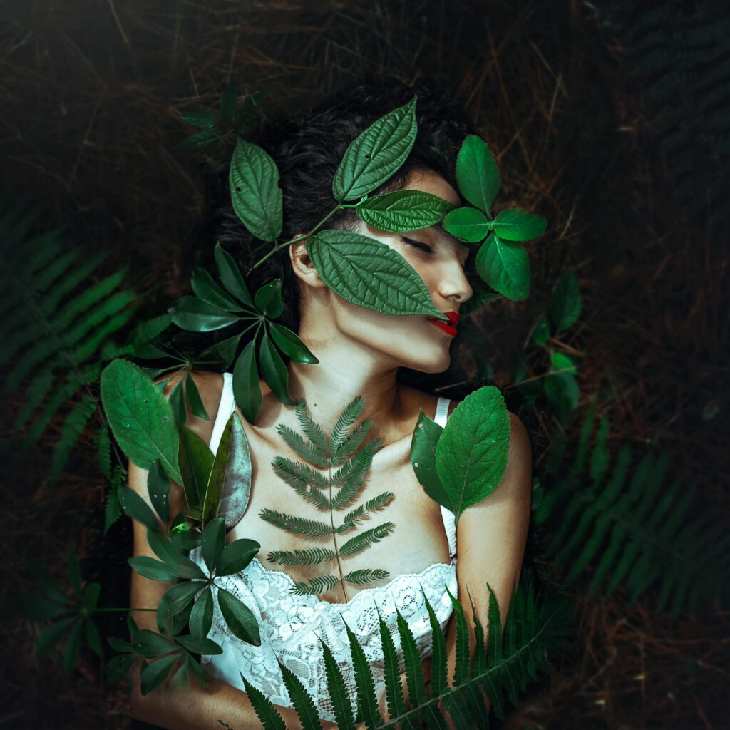 Serene portrait of a woman lying amidst vibrant green leaves, emphasizing a fusion with nature.